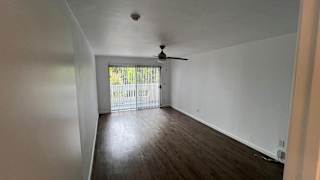 A room with a ceiling fan and sliding glass doors leading to a balcony.
