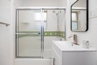 A white bathroom with a glass shower door and a white sink.