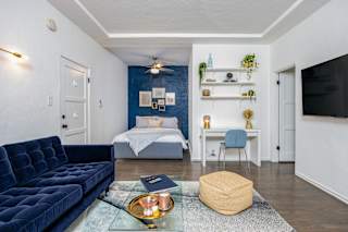 a living room with a blue couch and a bed