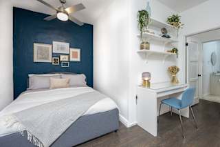 a bedroom with a blue accent wall and a white bed