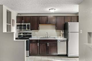 A kitchen with brown cabinets and a white refrigerator.