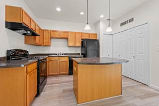 A kitchen with wooden cabinets and a black fridge.