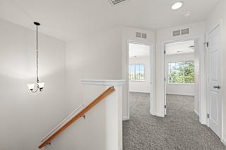 A white room with a staircase and a chandelier.