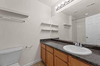 A bathroom with a white tub, sink, and mirror.