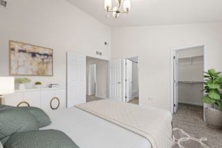 A bedroom with a bed, a couch, and a painting on the wall.