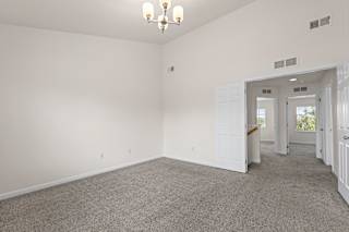 A spacious room with a carpeted floor and a chandelier hanging from the ceiling.