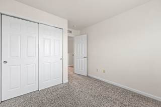 A room with white doors and carpeted floor.