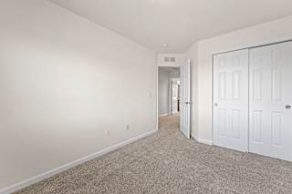 A spacious room with white walls and carpeted floor.