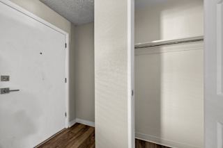 A white door is open to a room with a white wall and a white closet.