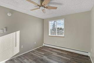 A room with a ceiling fan and a window with blinds.