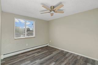 A room with a ceiling fan and a window with blinds.
