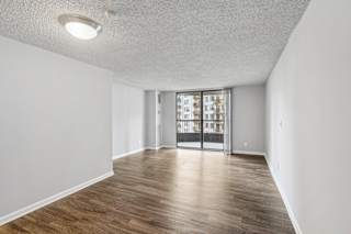 an empty living room with a sliding glass door to a balcony