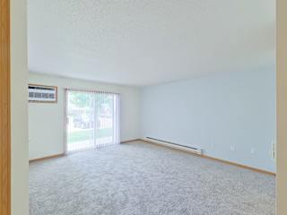 A room with a carpeted floor and a window with blinds.