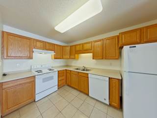 A kitchen with wooden cabinets and white appliances.