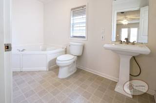 The master bathroom with sink, toilet, and large tub.