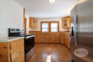 A kitchen with hardwood floors, wooden cabinets and a stainless steel refrigerator.