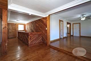 The foyer of a two bedroom two bath home with wooden accents, stairs leading into the basement, and living room.