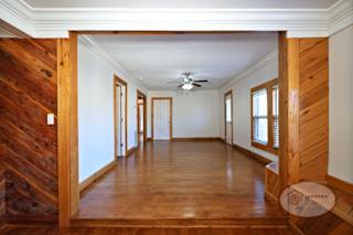 The living room with hardwood flooring, white walls, and large windows.