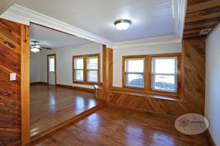 The foyer of a two bedroom two bath home with wooden accents, stairs leading into the basement, and living room.