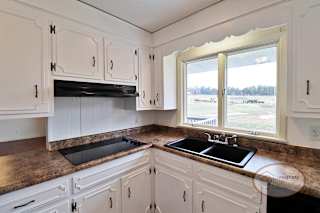 A kitchen with white cabinets and black cooktop.