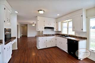 A kitchen with plenty of white cabinets and hardwood floors.