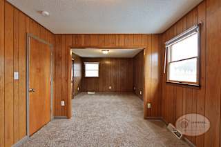 A bedroom with wood paneling, carpet, and room divider.