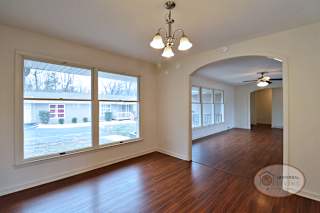 The dining room with arch way, large windows, and hardwood flooring.