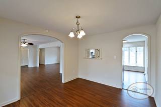 The dining room with arched doorways, serving window, and hardwood floors.