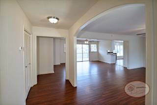 A spacious living room with wood flooring and white walls.