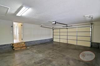 A spacious garage with a door leading to the main house.