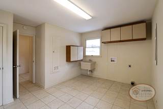 The laundry room with tile, white walls, and cabinets.