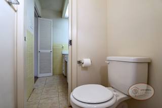 A bathroom with toilet, tile, large counter, and shower over tub.
