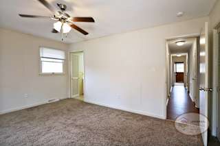 The master bedroom with carpet, bathroom, and ceiling fan.