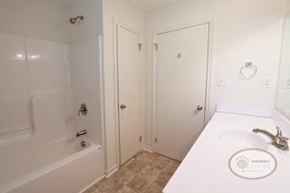 A bathroom with a tub, sink and closet.