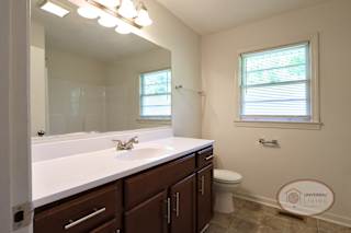 A bathroom with a sink and large vanity, mirror, and window.