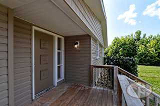 The porch of a house with a tan door.