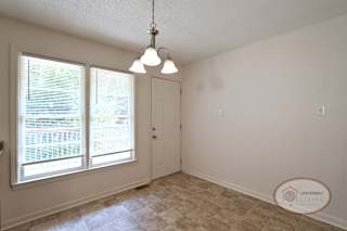 A dining area in the kitchen with small light, door leading to the porch, and large windows