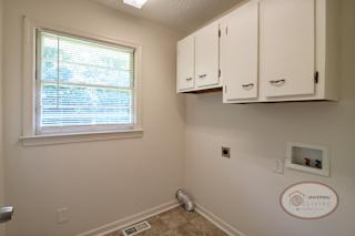 The laundry room with cabinets, vinyl floor, and window.