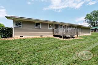 The rear of a grey home with a back deck.
