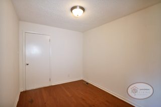 A small mudroom coming off of the garage with white walls and hardwood floors.