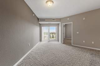 A room with a carpeted floor and a window with blinds.