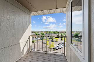 A balcony with a view of a parking lot and buildings.
