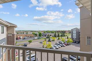 A balcony view of a parking lot with cars and buildings.