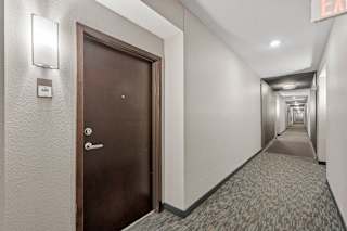 A hallway with a brown door and a sign that says "EXIT".