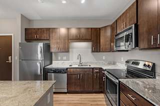 A kitchen with a granite counter top and stainless steel appliances.