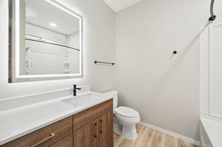 A white bathroom with a toilet, sink, and mirror.