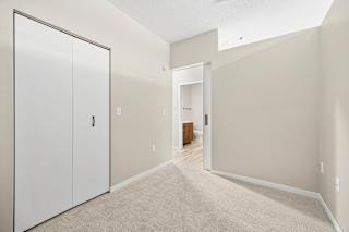 A hallway with a white door on the left and a white closet door on the right.