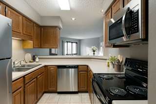 A kitchen with a stove, sink, and microwave.
