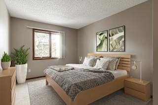A bedroom with a bed, nightstand, and two potted plants.