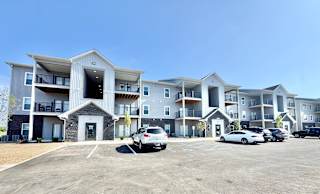 A row of modern apartment buildings with cars parked in front.